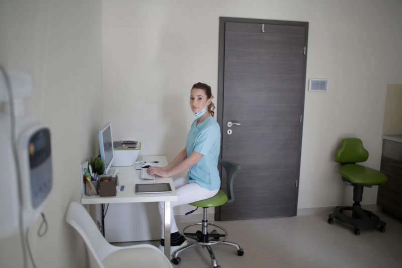 A clinic receptionist handling an online booking at a computer
