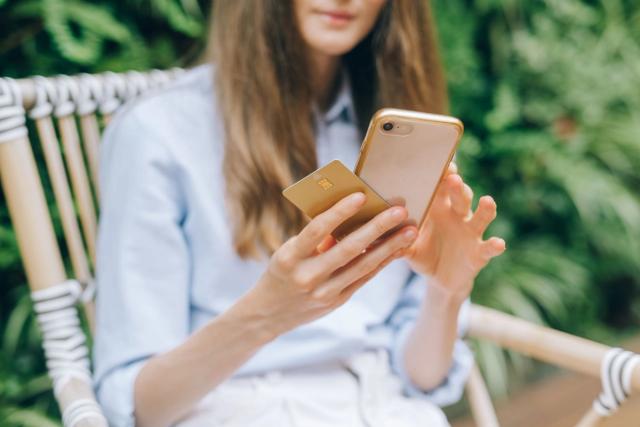 A woman making an online purchase using a smartphone and credit card, illustrating fintech payment security