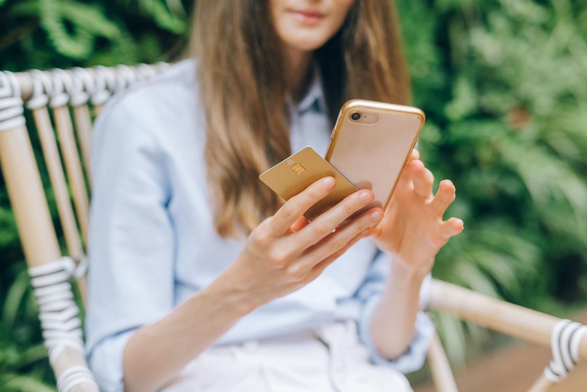 A woman making an online purchase using a smartphone and credit card, illustrating fintech payment security