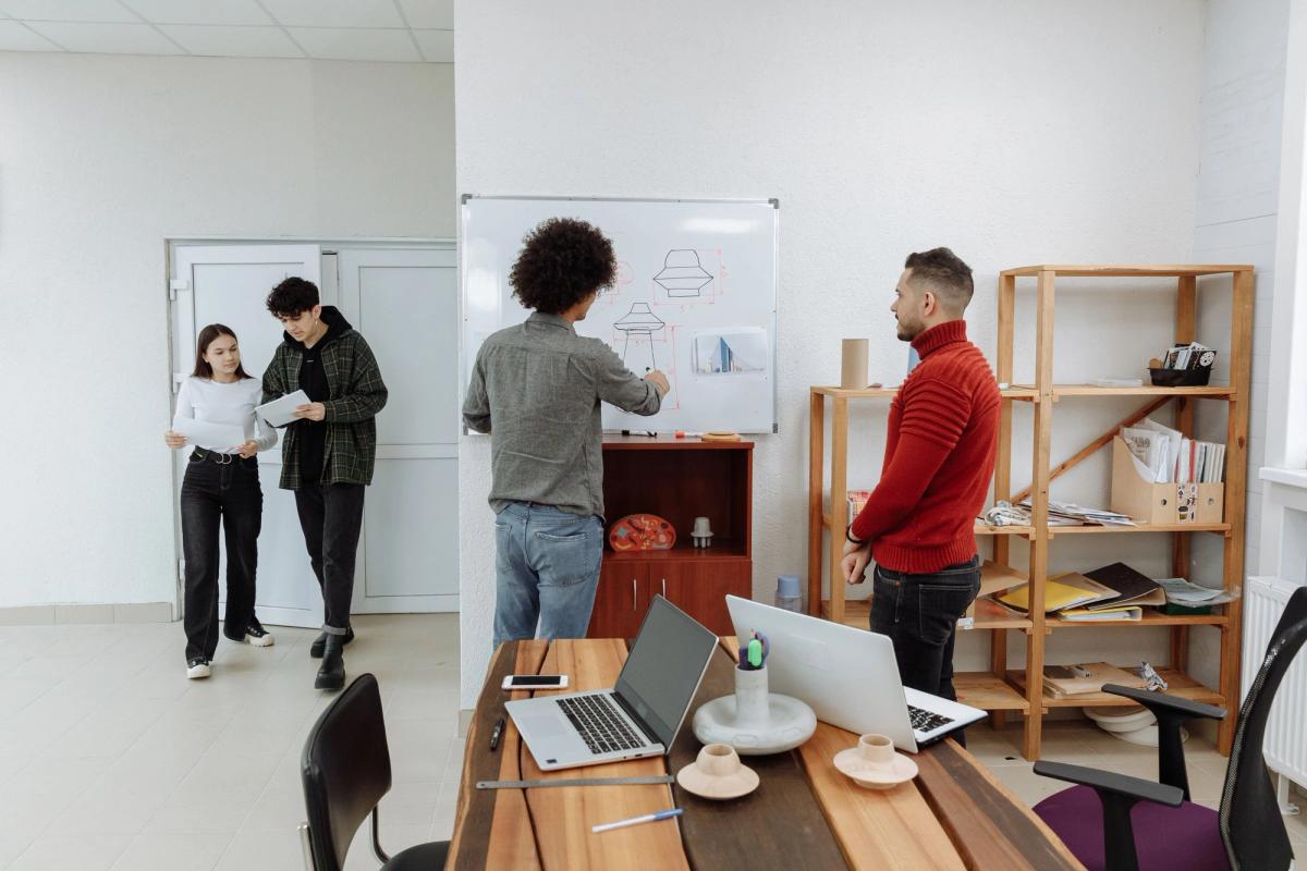 Members of a team discussing requirements at a whiteboard in a modern office