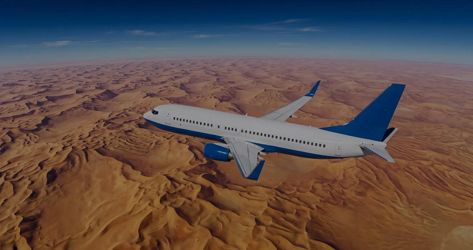 Aerial view of a plane flying over desert dunes