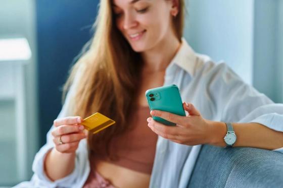 Woman holding a phone and a payment card