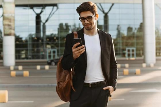 Traveller using his phone outside an airport terminal