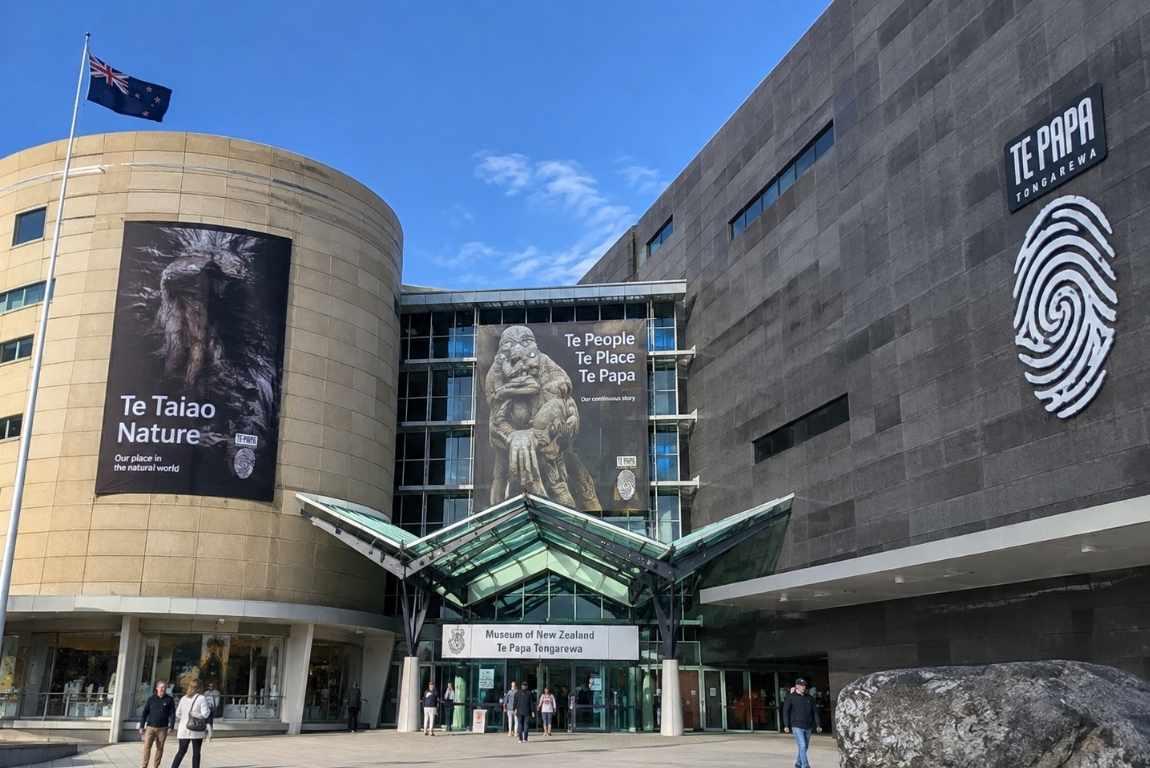 Exterior of the Museum of New Zealand Te Papa Tongarewa in Wellington, with exhibition banners and the New Zealand flag.