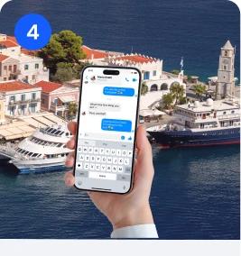 Hand holding a phone with a messaging app open, overlooking a Mediterranean ferry port