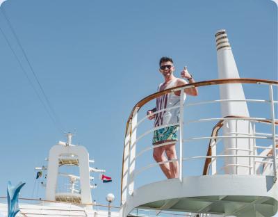 Cruise passenger waving from the deck of a docked cruise ship