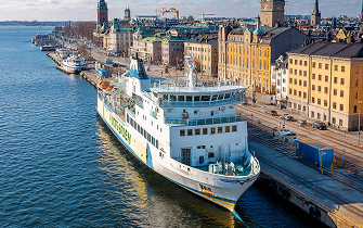 Ferry docked in a busy harbor surrounded by waterfront buildings