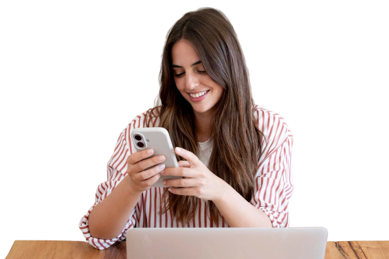 Woman smiling while using her phone at a laptop