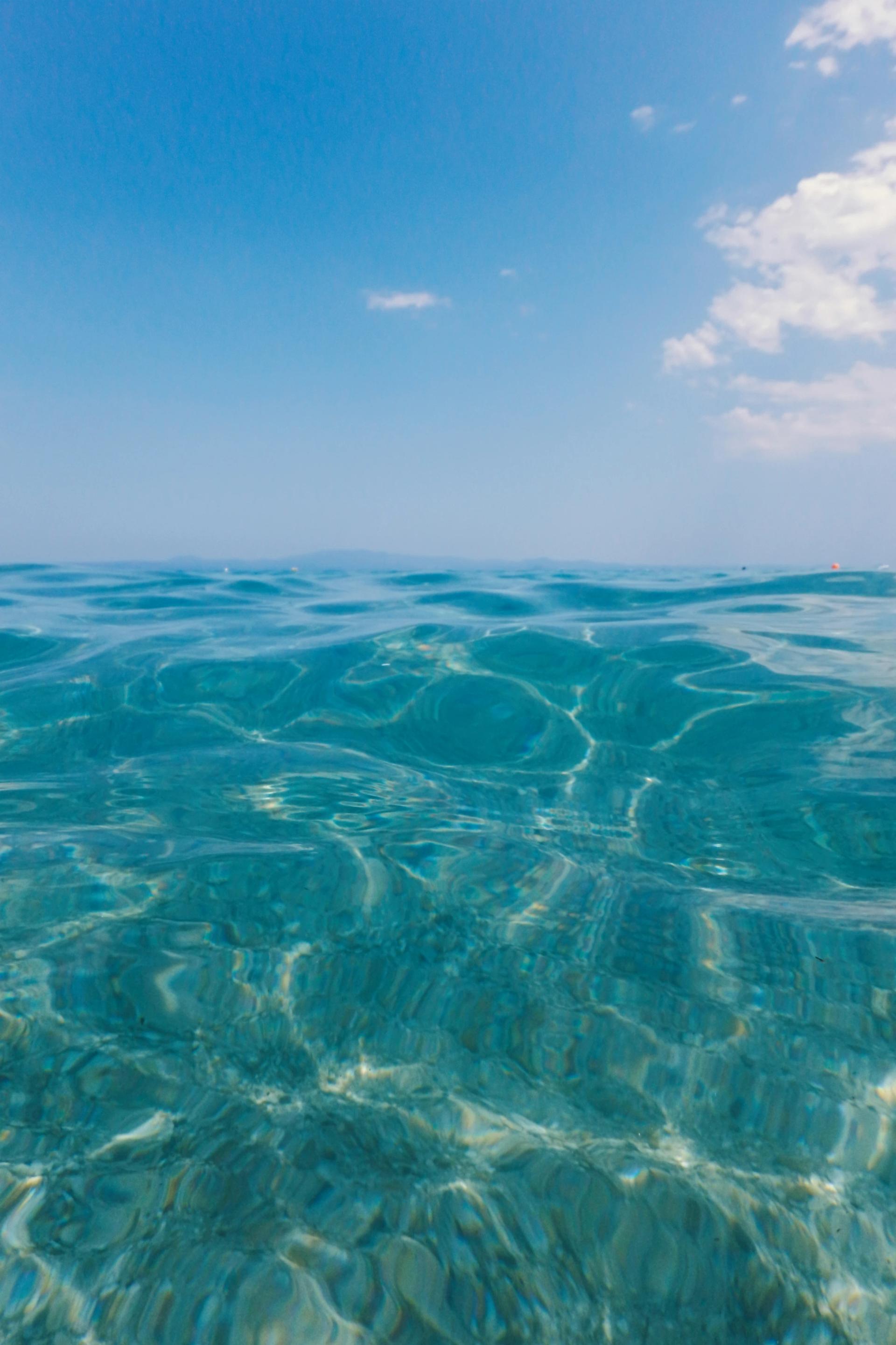 Clear turquoise ocean water under a blue sky with light clouds