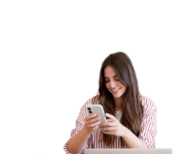 Woman smiling while using her phone at a laptop