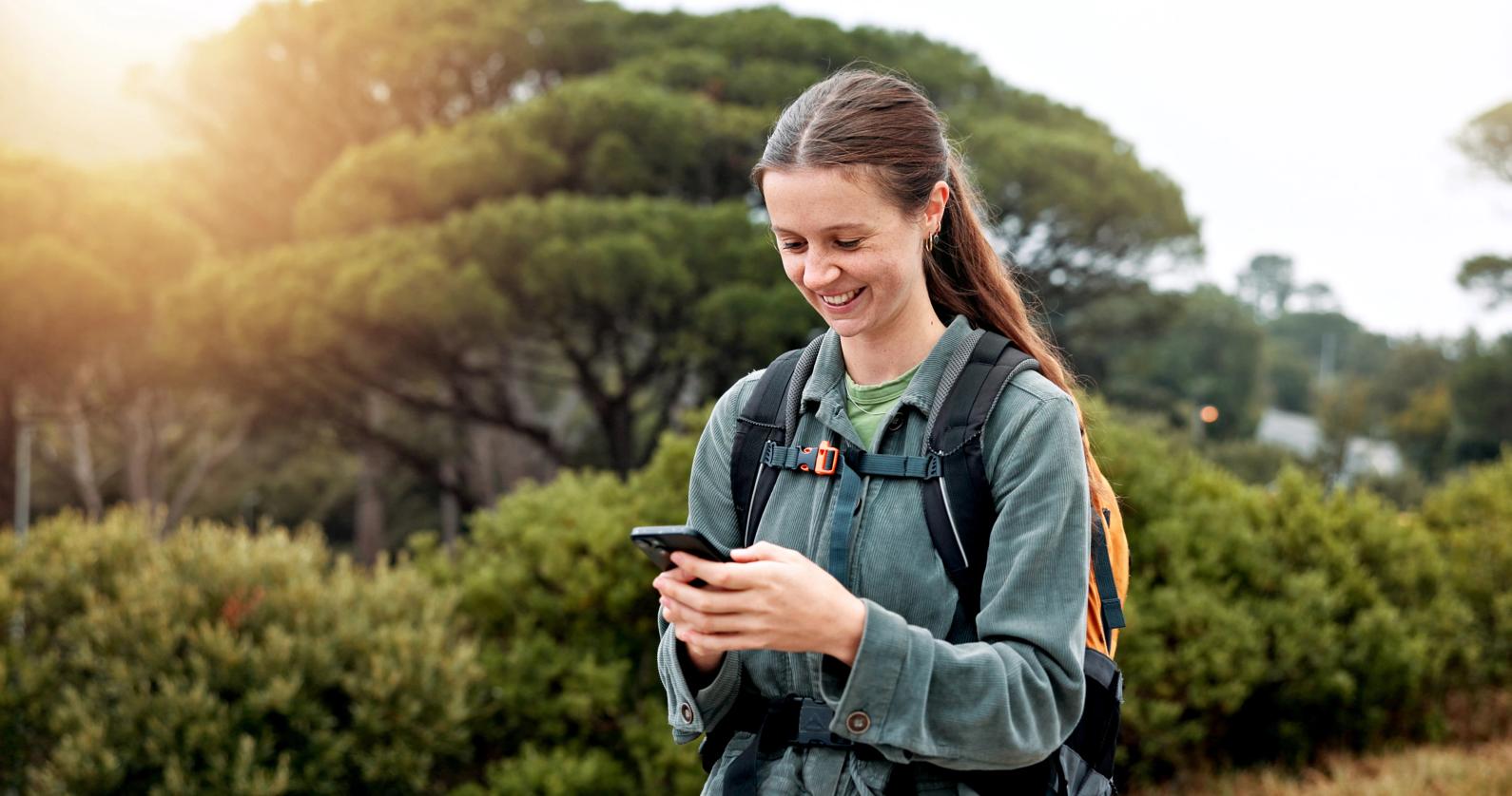 屋外でバックパックを背負いスマートフォンを確認する旅行者