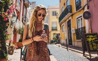 Woman checking her phone while walking through a coastal town after leaving the ferry