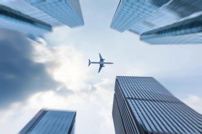 Airplane flying over city towers