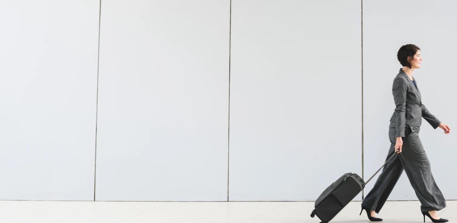 Woman walking with a suitcase in an office corridor