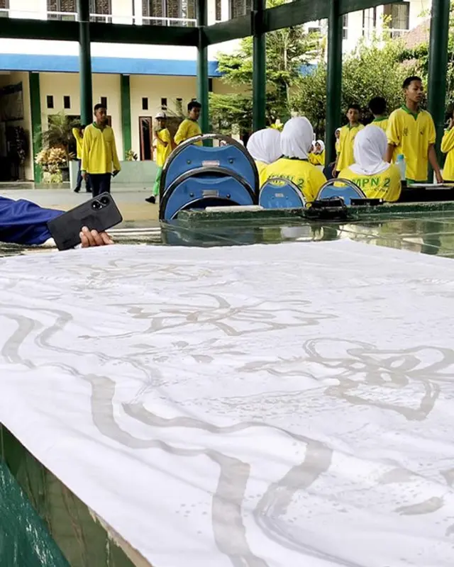 Pengrajin Batik TGP sedang mengerjakan dan menampilkan kain batik tulis khas Malangan di ruang produksi.