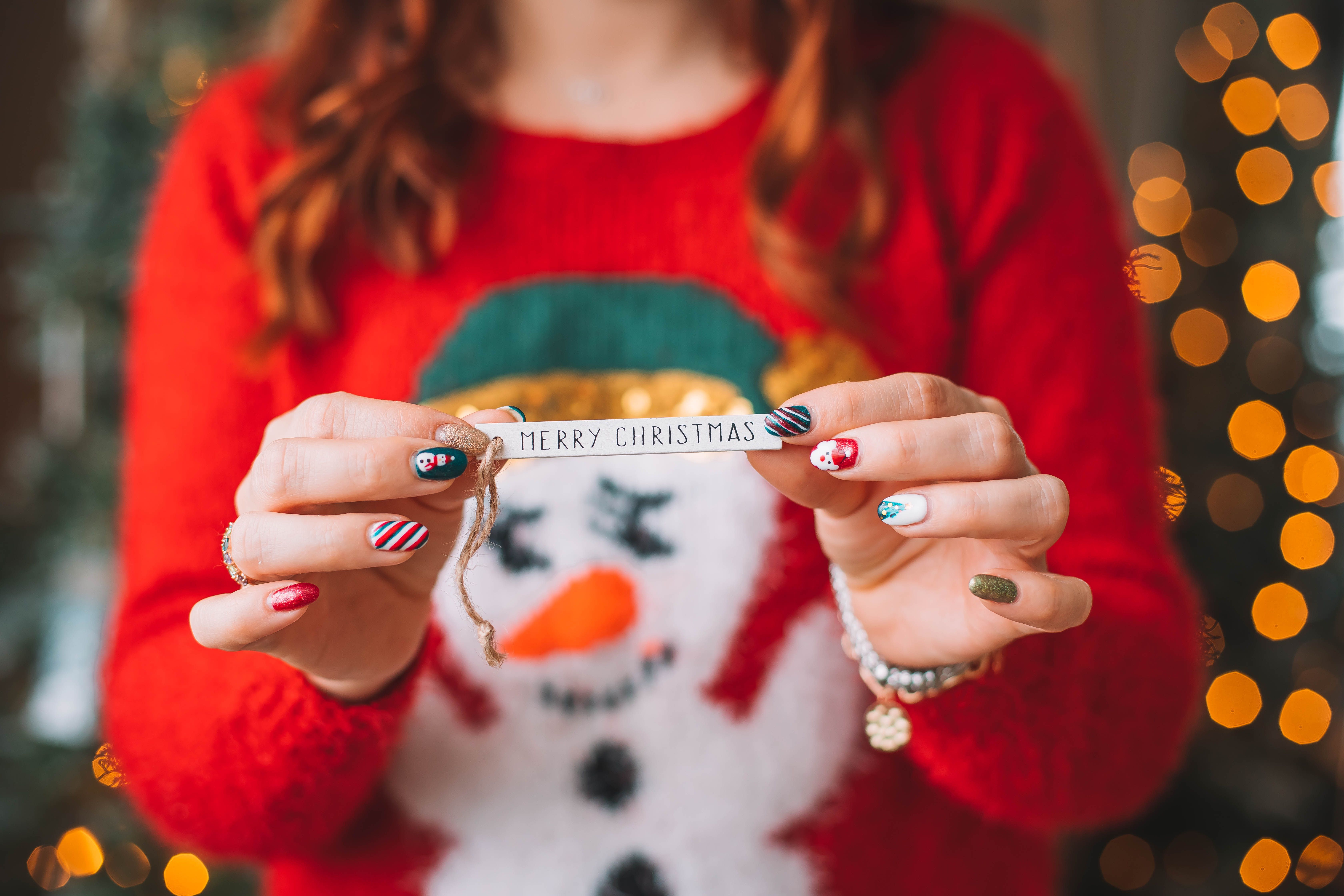 jeune fille ayant un nail art tient un papier "merry christmas" 