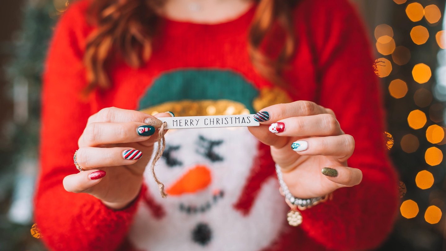 jeune fille ayant un nail art tient un papier "merry christmas"