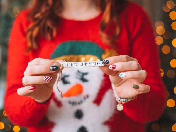 jeune fille ayant un nail art tient un papier "merry christmas"