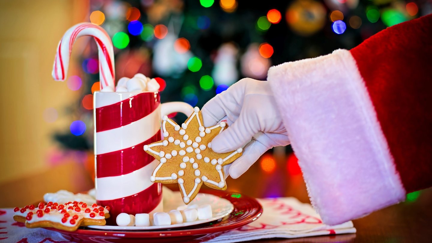 Main de père Noel qui tient un biscuit