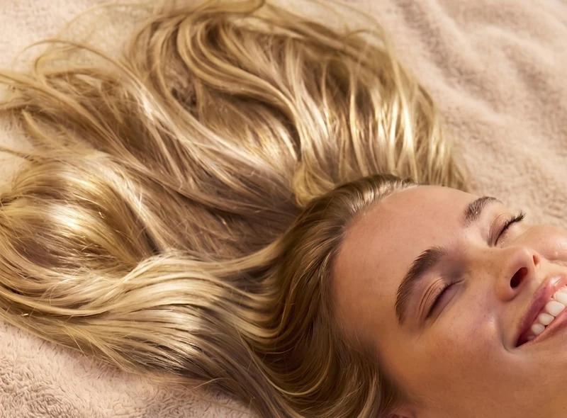 tête de femme blonde allongée et souriante
