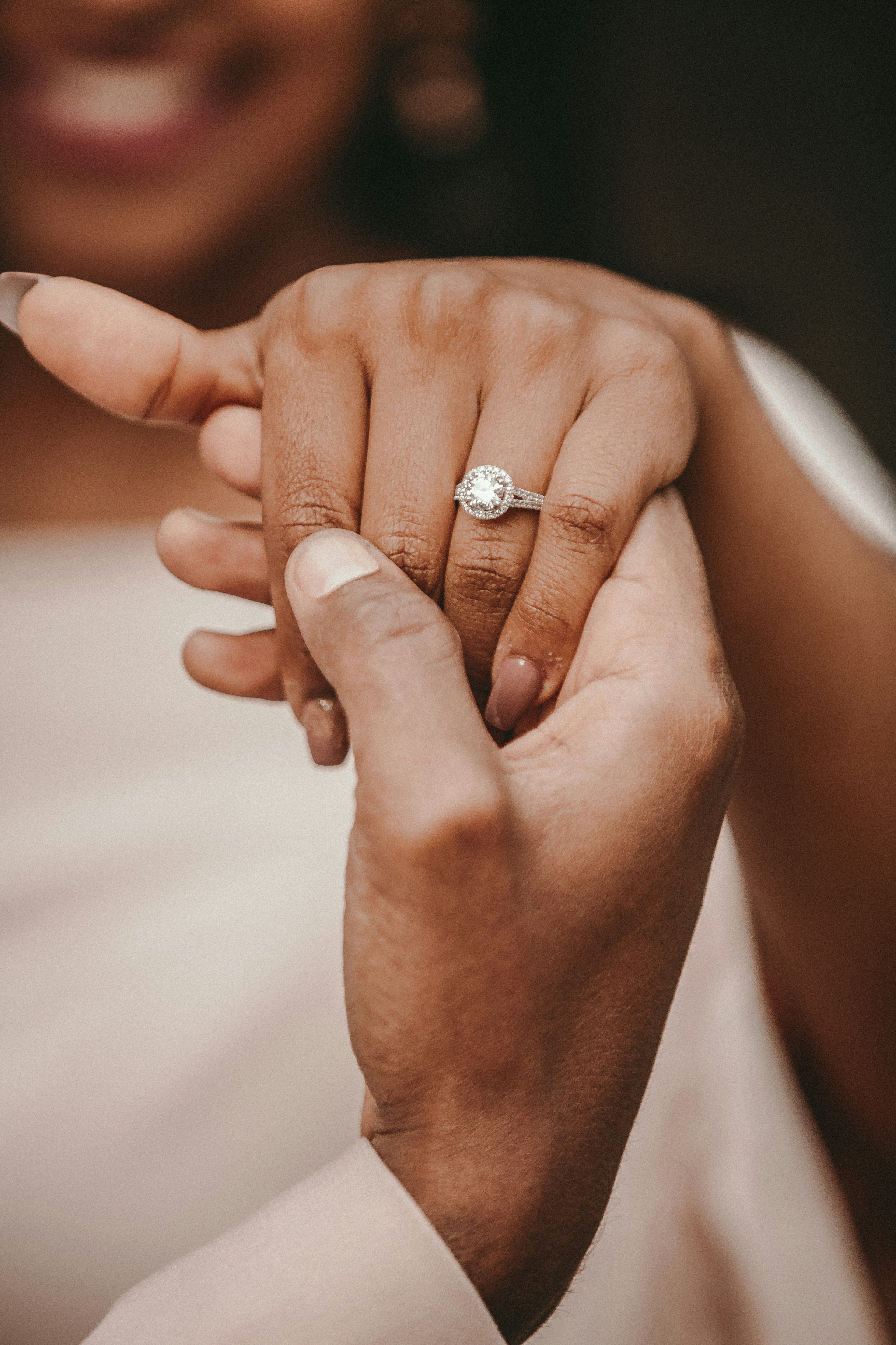 Close-up of joined hands, one wearing a diamond engagement ring