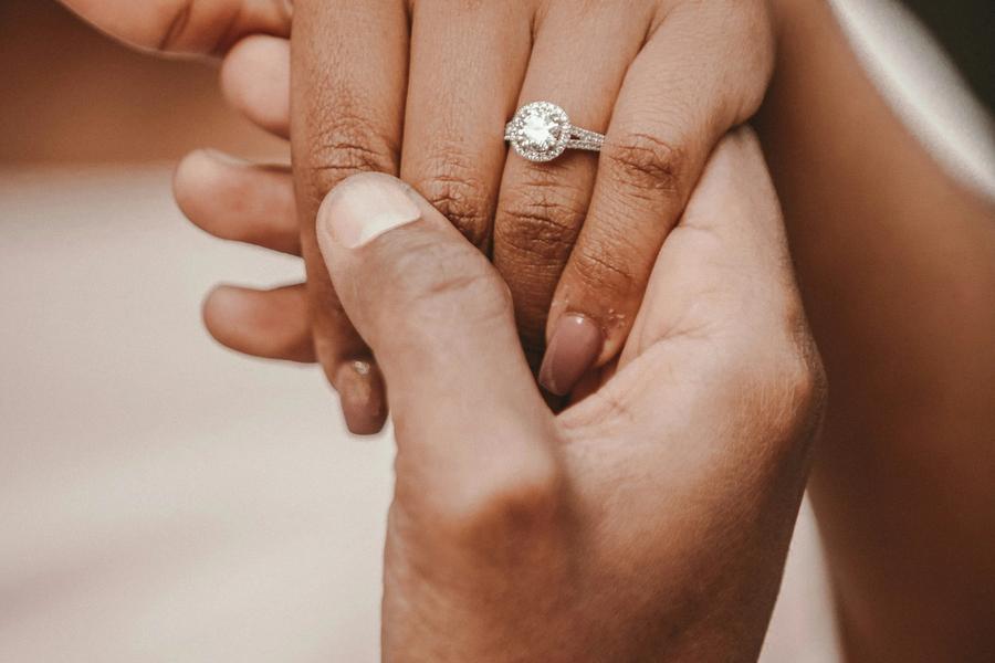 Close-up of joined hands, one wearing a diamond engagement ring