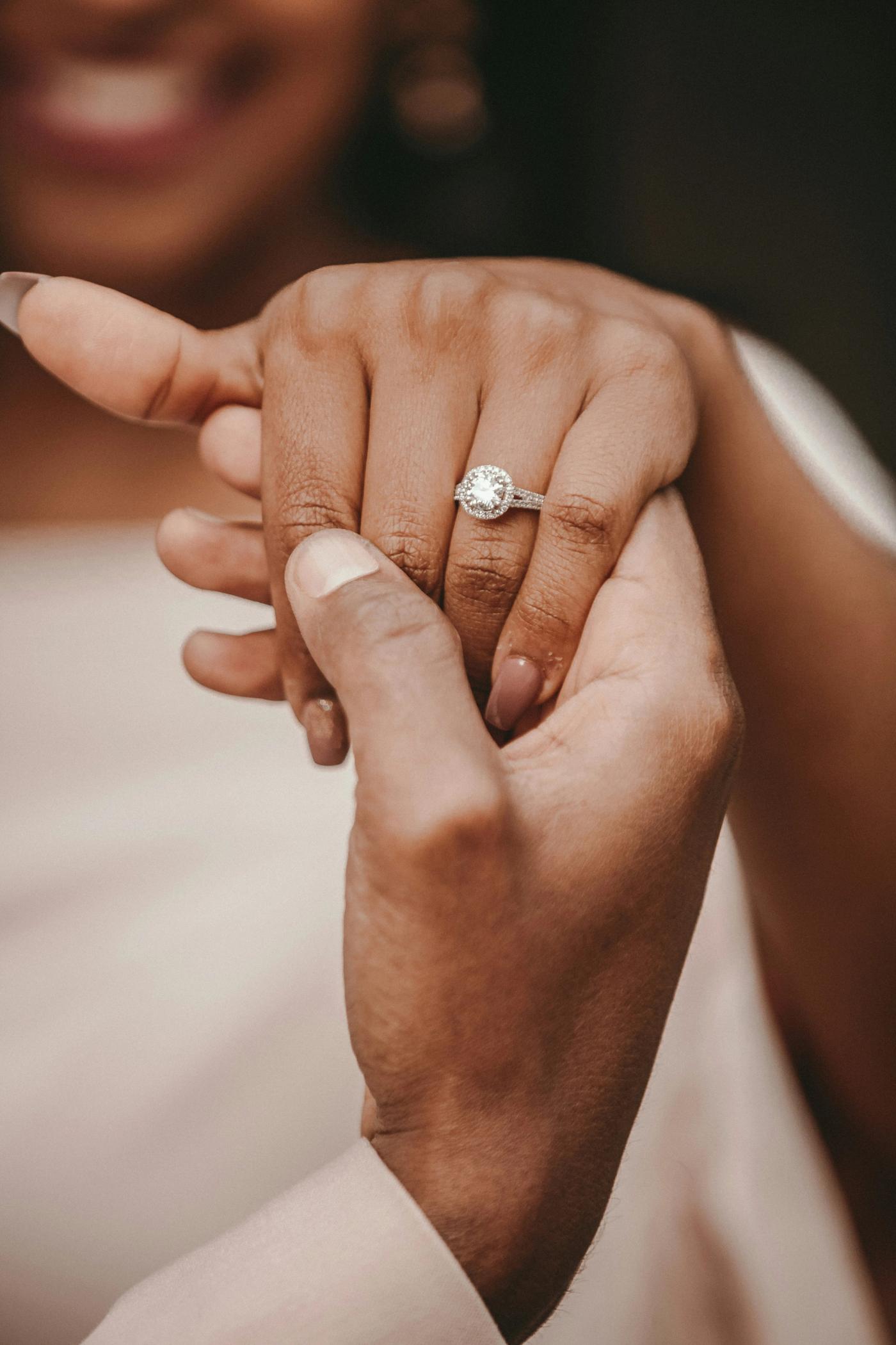 Close-up of joined hands, one wearing a diamond engagement ring