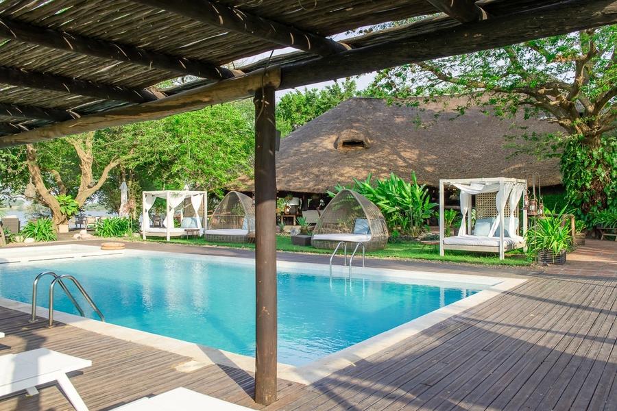 Swimming pool with canopy daybeds and the thatched restaurant behind