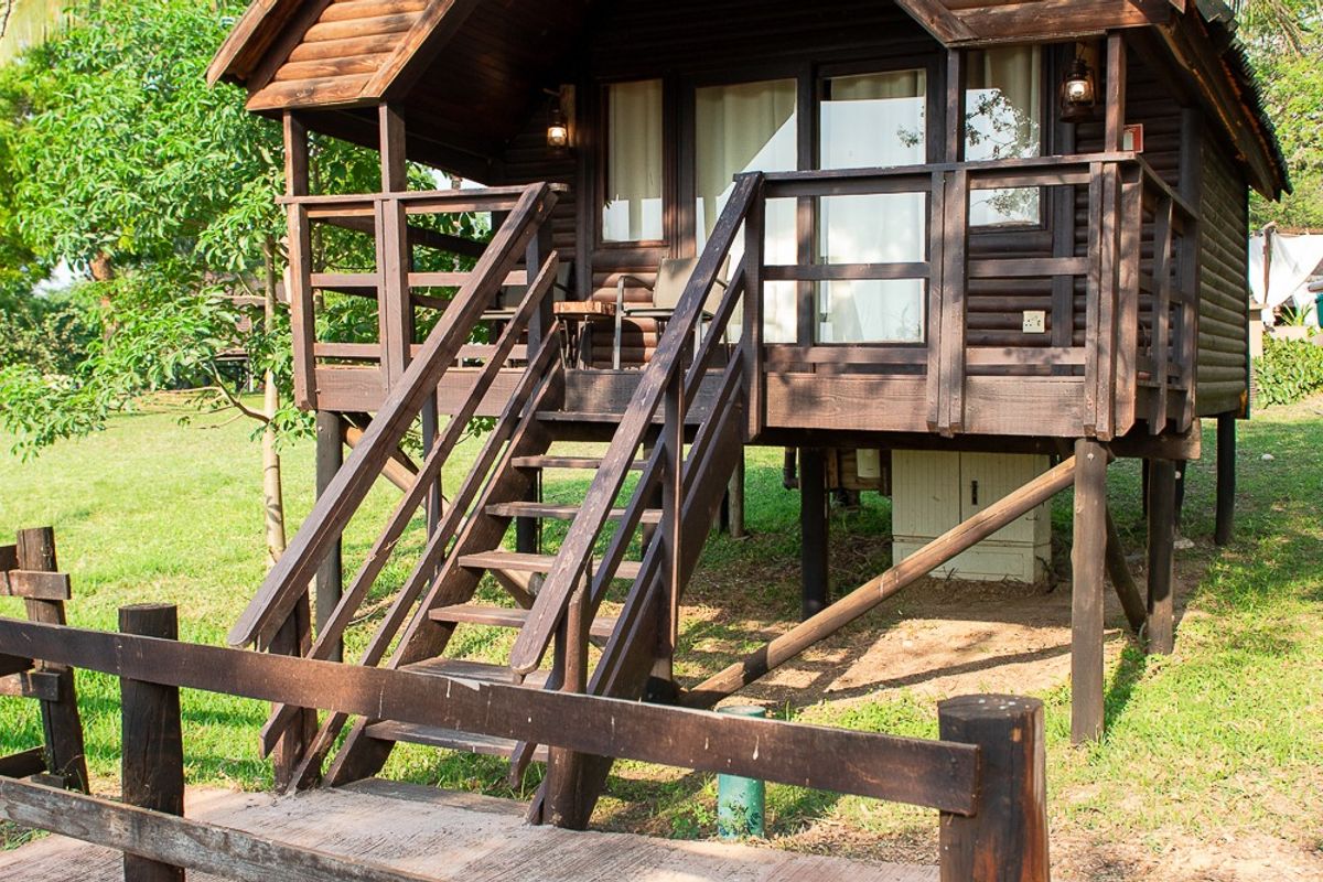 A-frame wooden cabana on stilts with steps up to its veranda