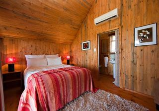 Wood-panelled bedroom with a double bed, a striped red bedspread and air conditioning