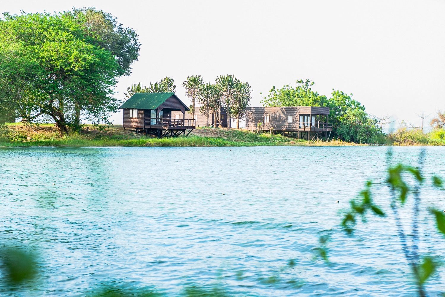 Wooden cabanas on stilts at the water's edge, seen across the Kilunda Lagoon