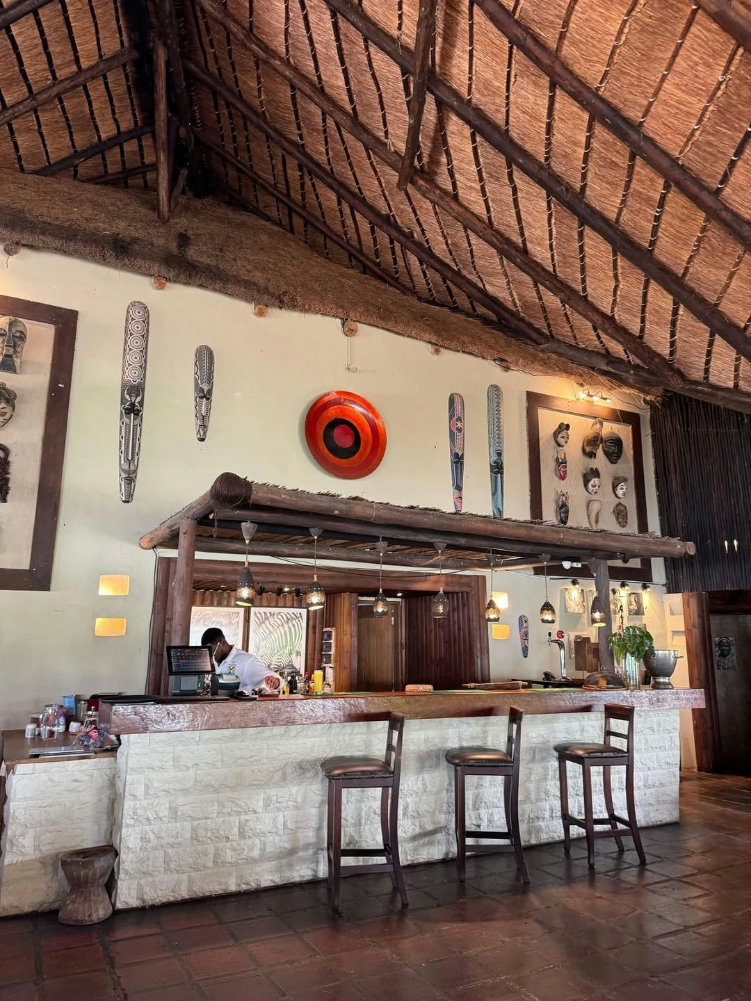 Bar counter with stools under a thatched roof, African masks on the walls