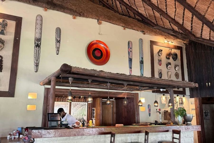 Bar counter with stools under a thatched roof, African masks on the walls