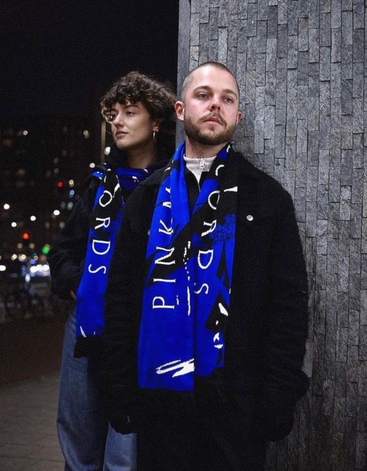 Two people in blue Pinkman Records scarves at night