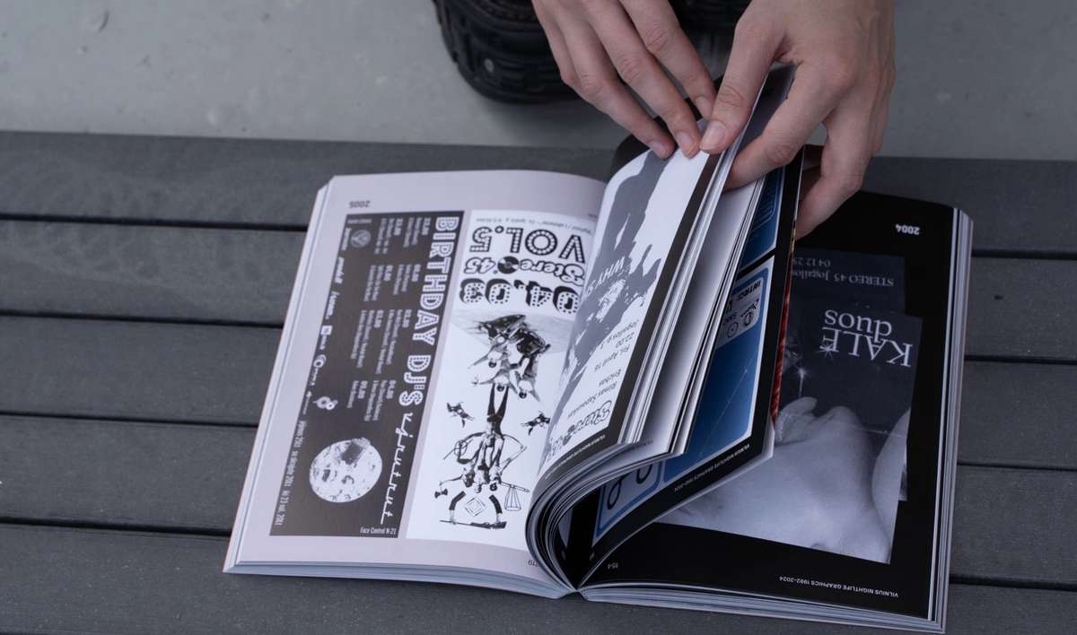 Hands turning pages of Vilnius Nightlife Graphics