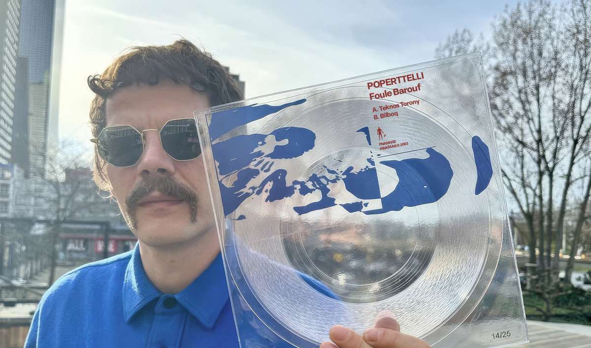A man in sunglasses holding up a clear vinyl record with a blue sleeve outdoors