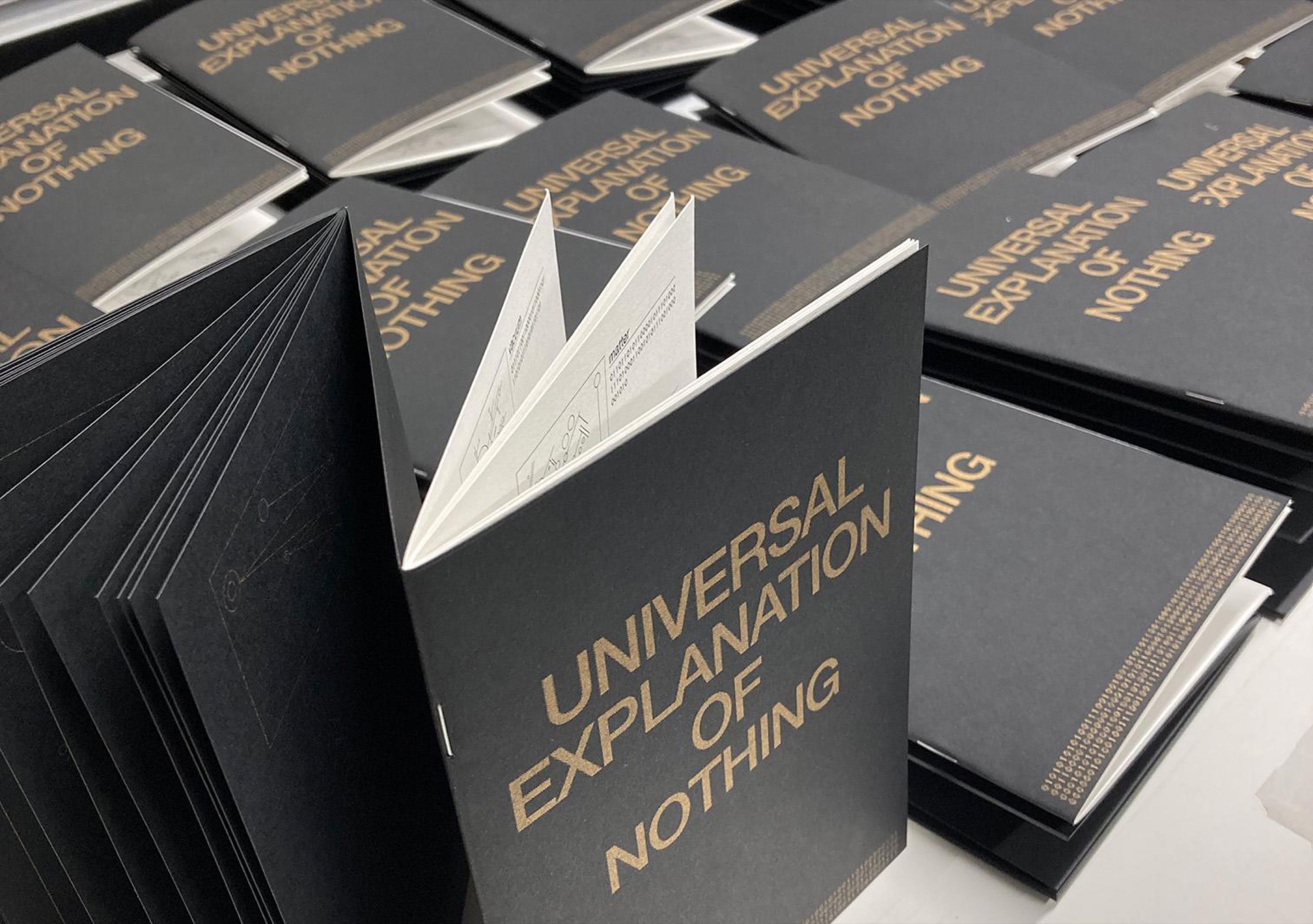 Stacks of Universal Explanation of Nothing books, one standing open