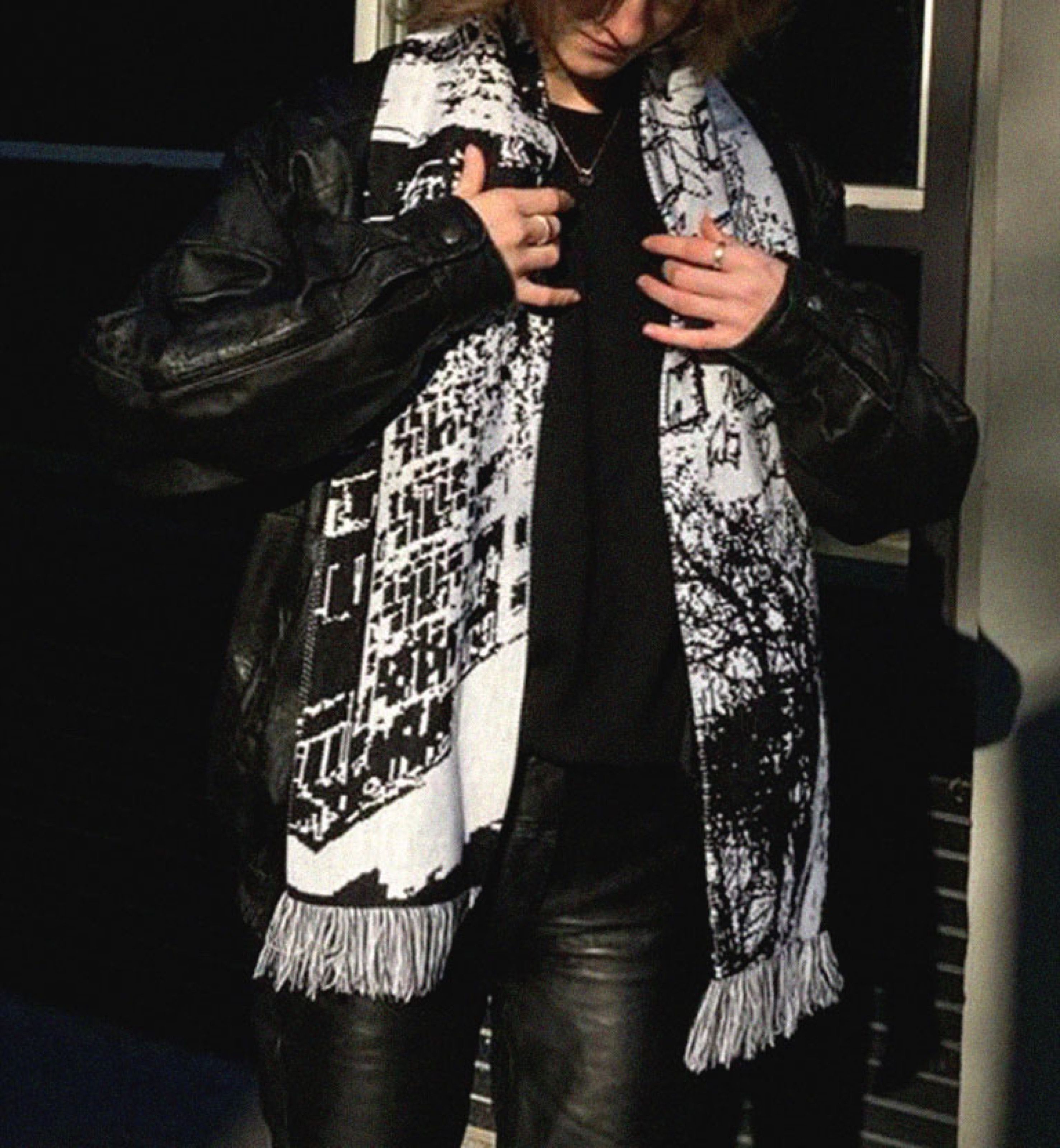 Person wearing a black-and-white jacquard scarf with forest imagery