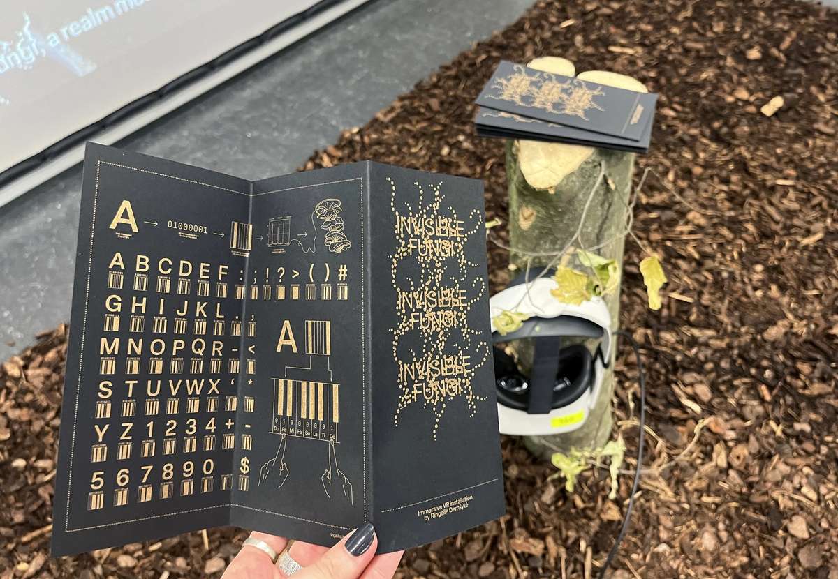 Hand holding an open Invisible Fungi booklet with a custom typeface
