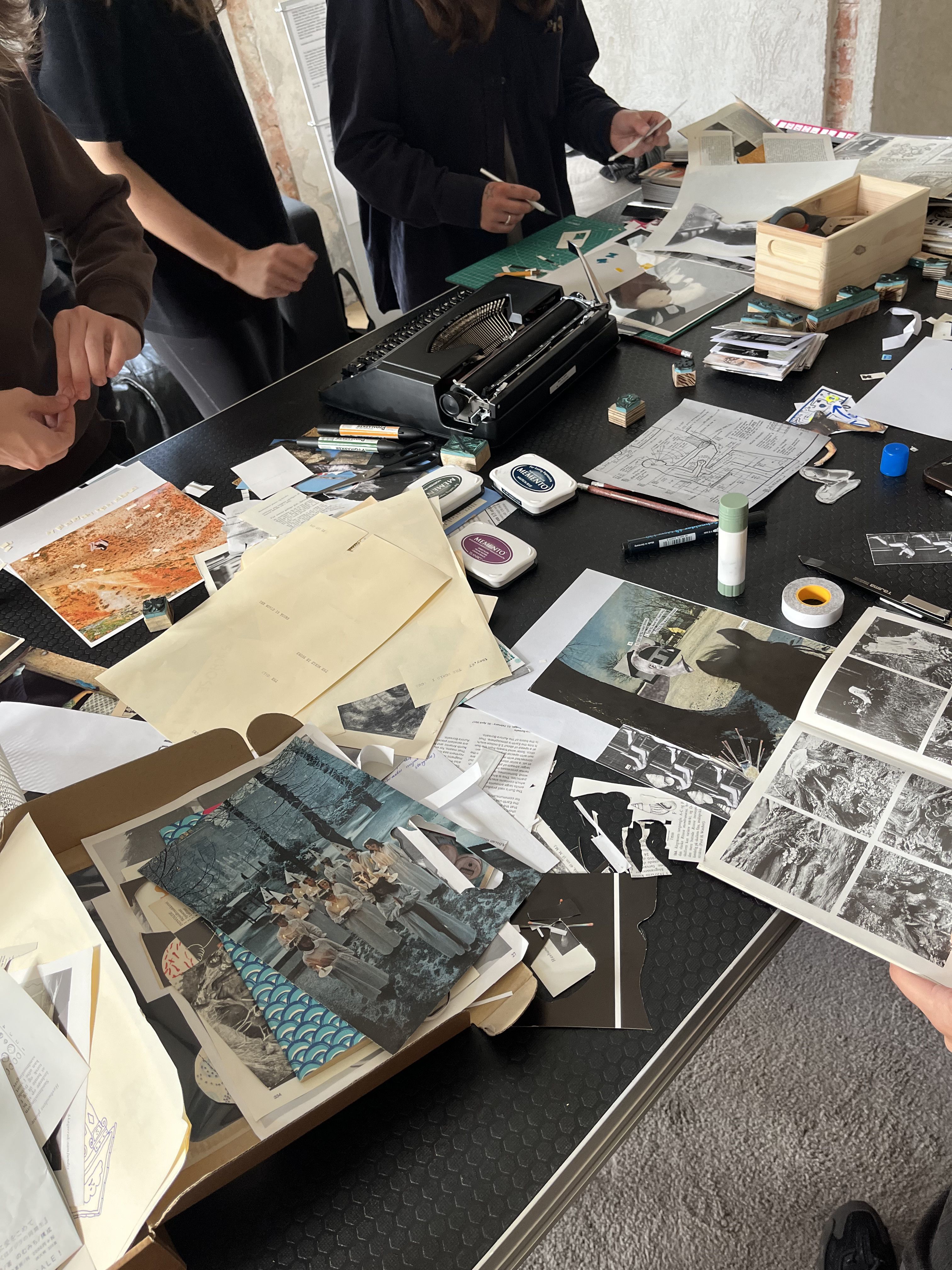 A table covered with cut-out images, glue and zine spreads