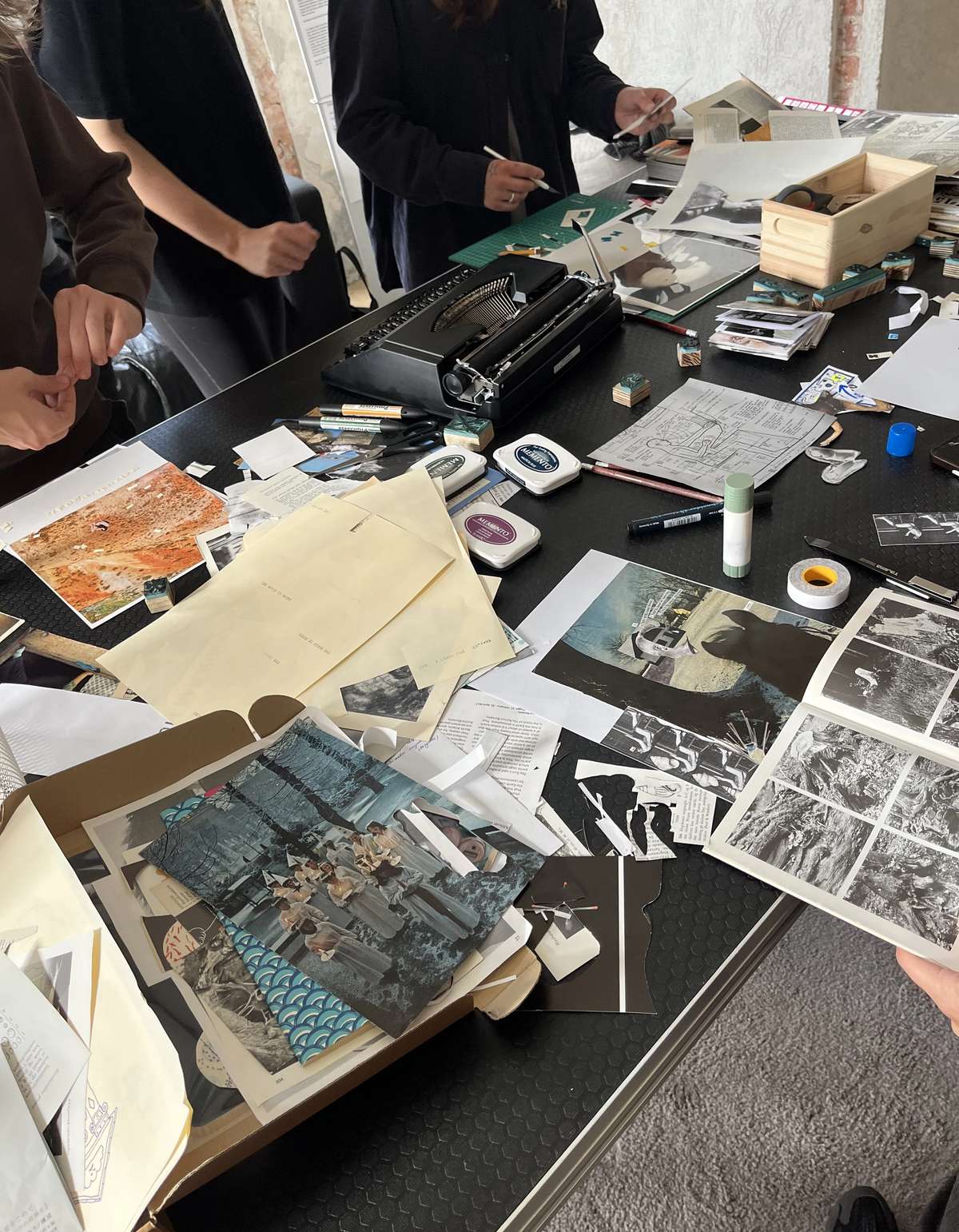 A table covered with cut-out images, glue and zine spreads