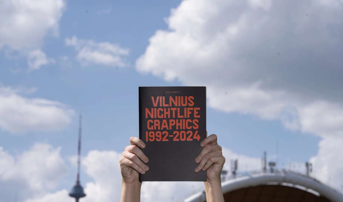 Hands holding Vilnius Nightlife Graphics 1992–2024 against the sky