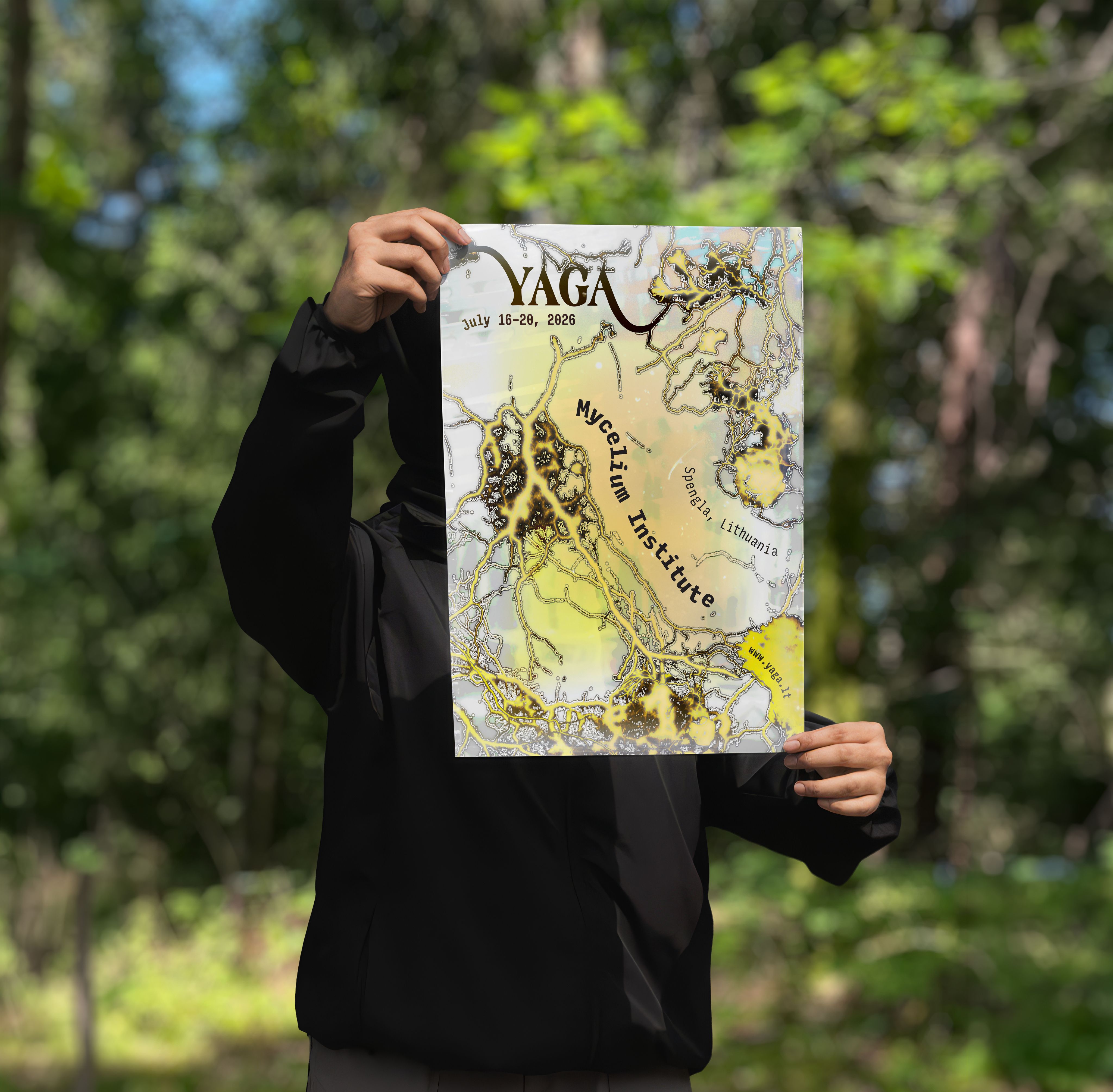 A person in a forest holding up the YAGA Gathering poster