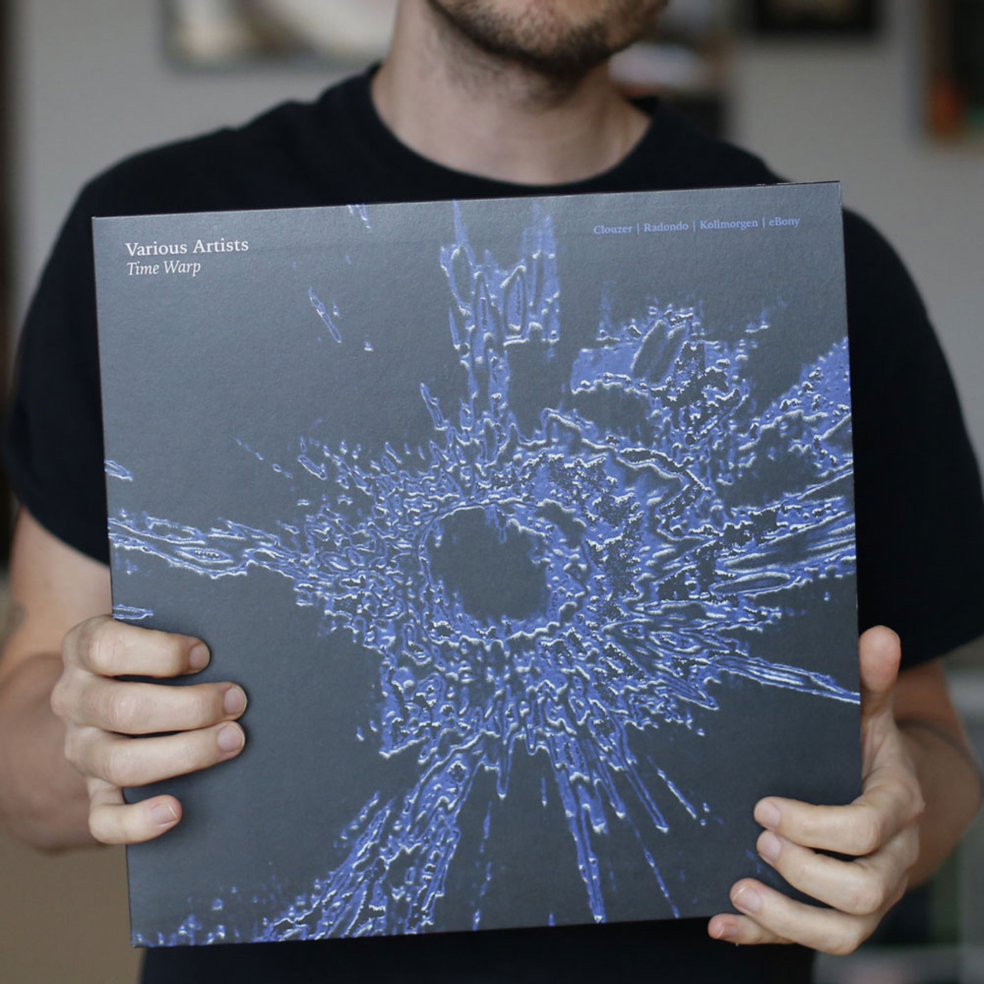 Person holding the Time Warp various artists vinyl sleeve with a blue crater print