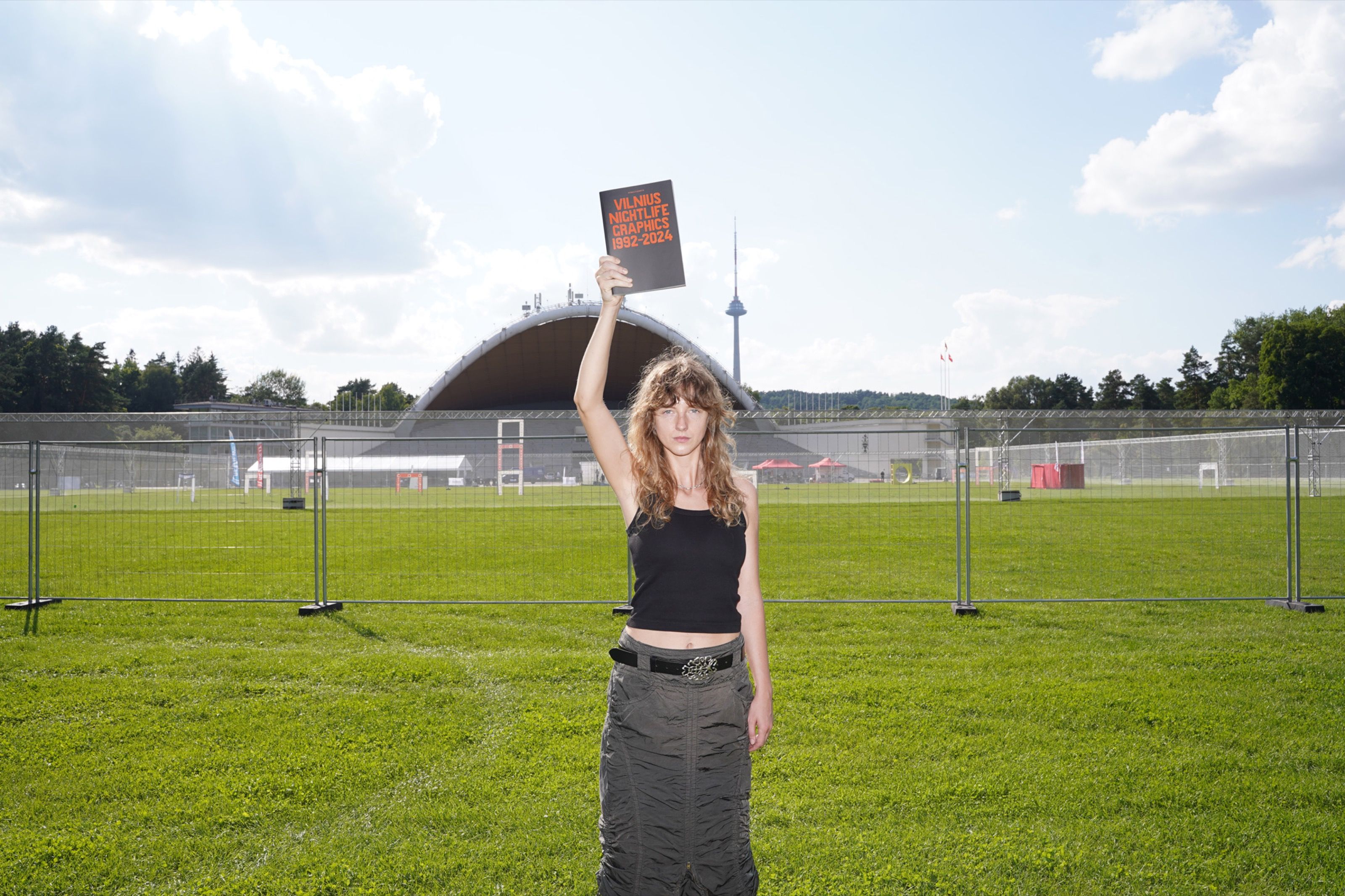 Ringailė Demšytė holding a book above her head in a grassy field