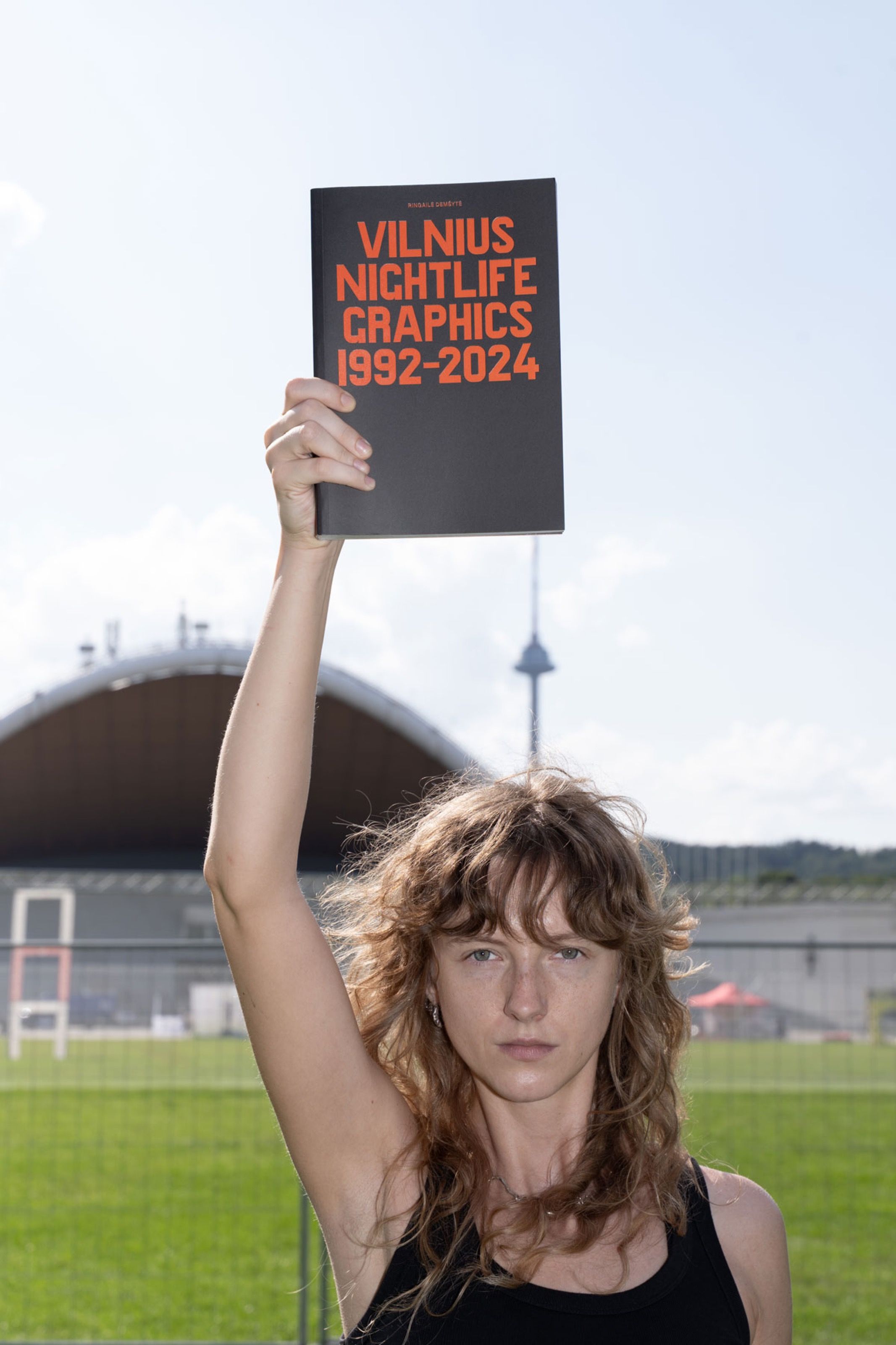 Ringailė Demšytė holding Vilnius Nightlife Graphics 1992–2024 above her head