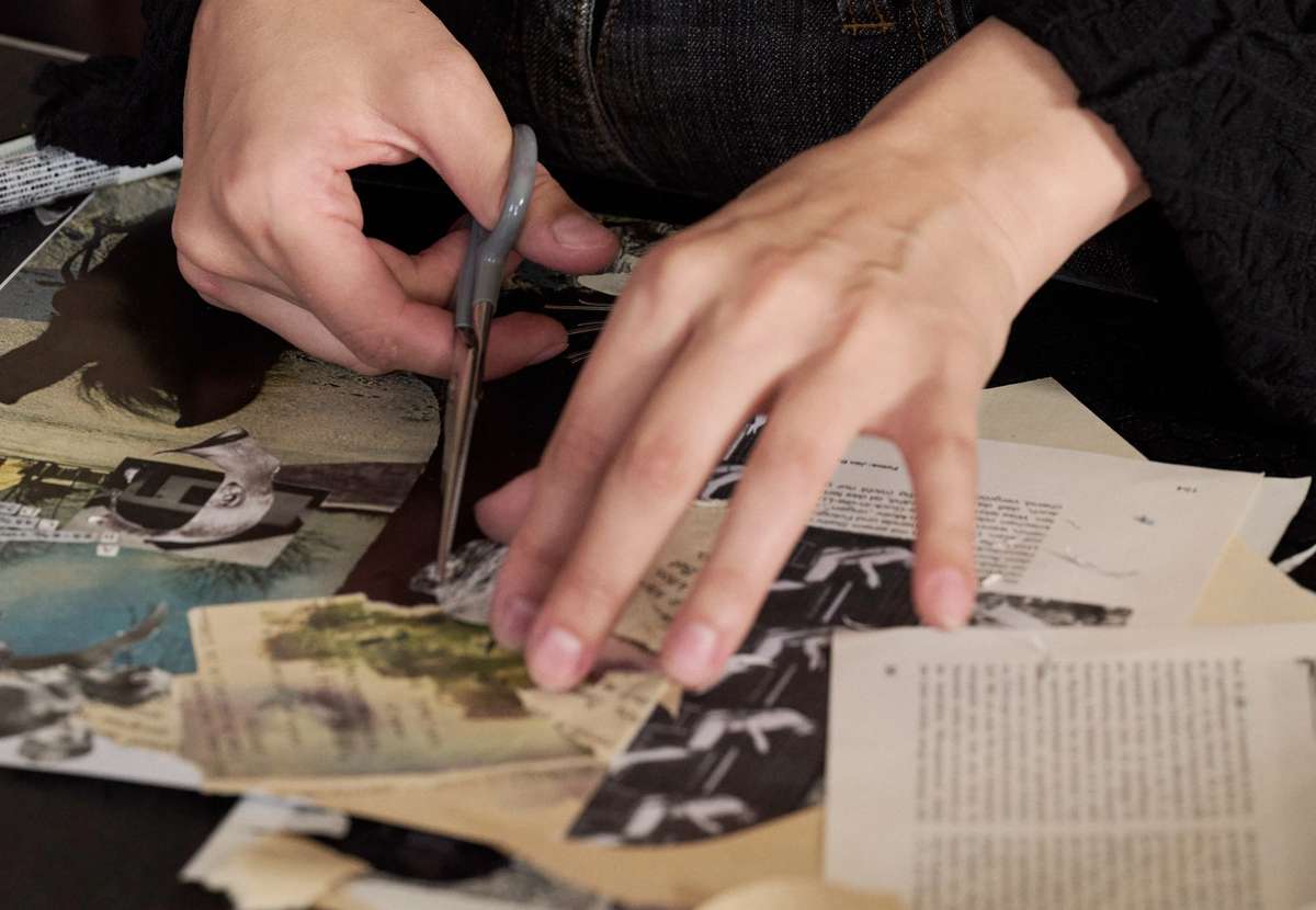Hands cutting out images for a zine collage