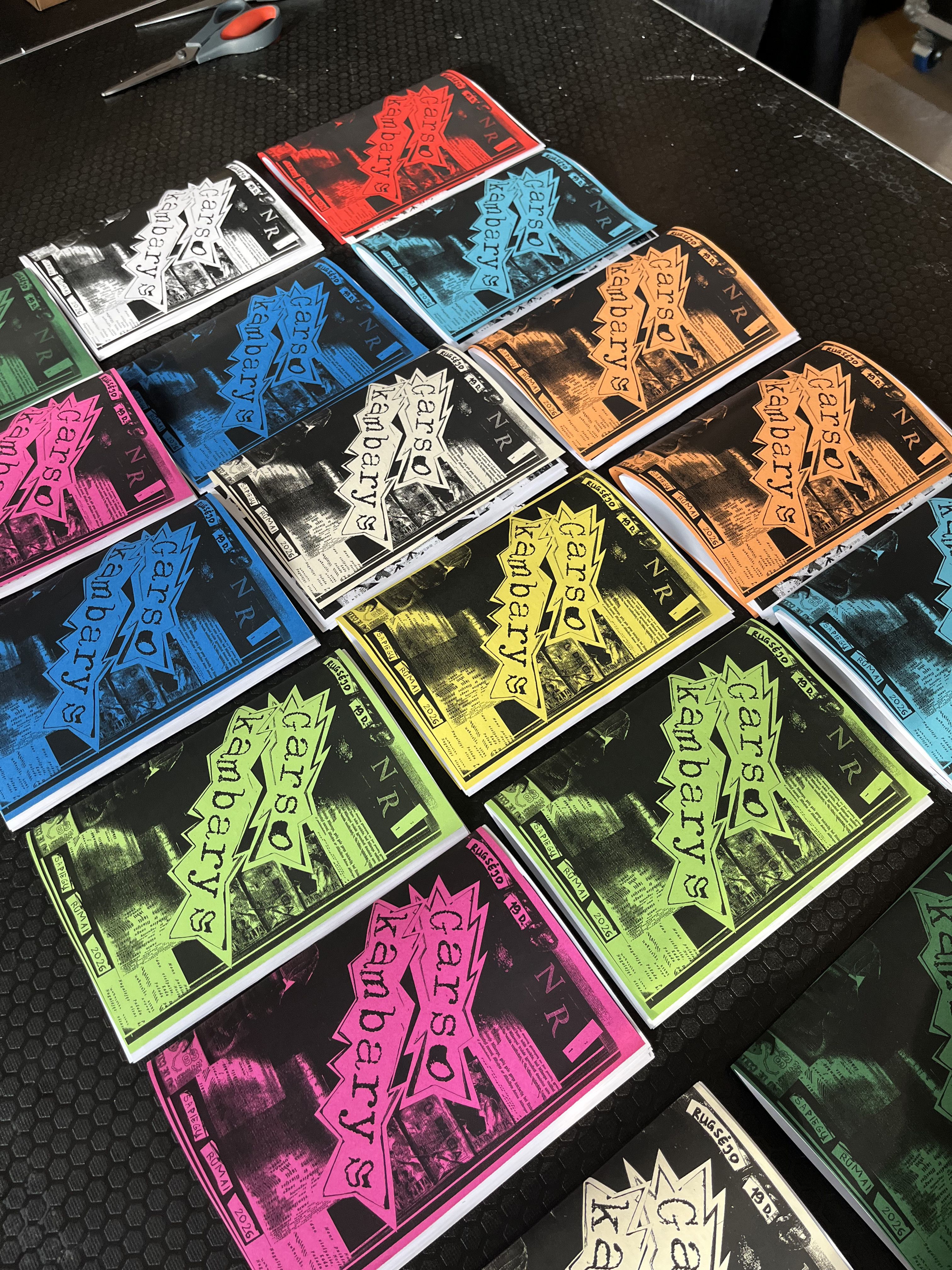 Printed zine covers in bright colours laid out on a table