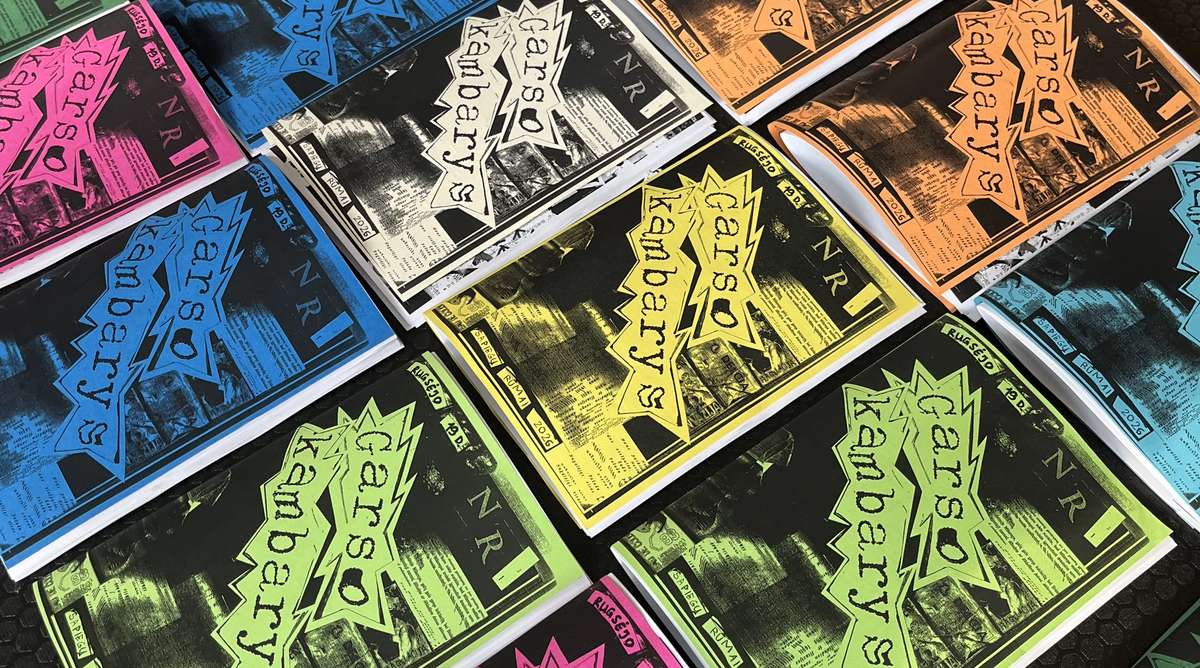 Printed zine covers in bright colours laid out on a table