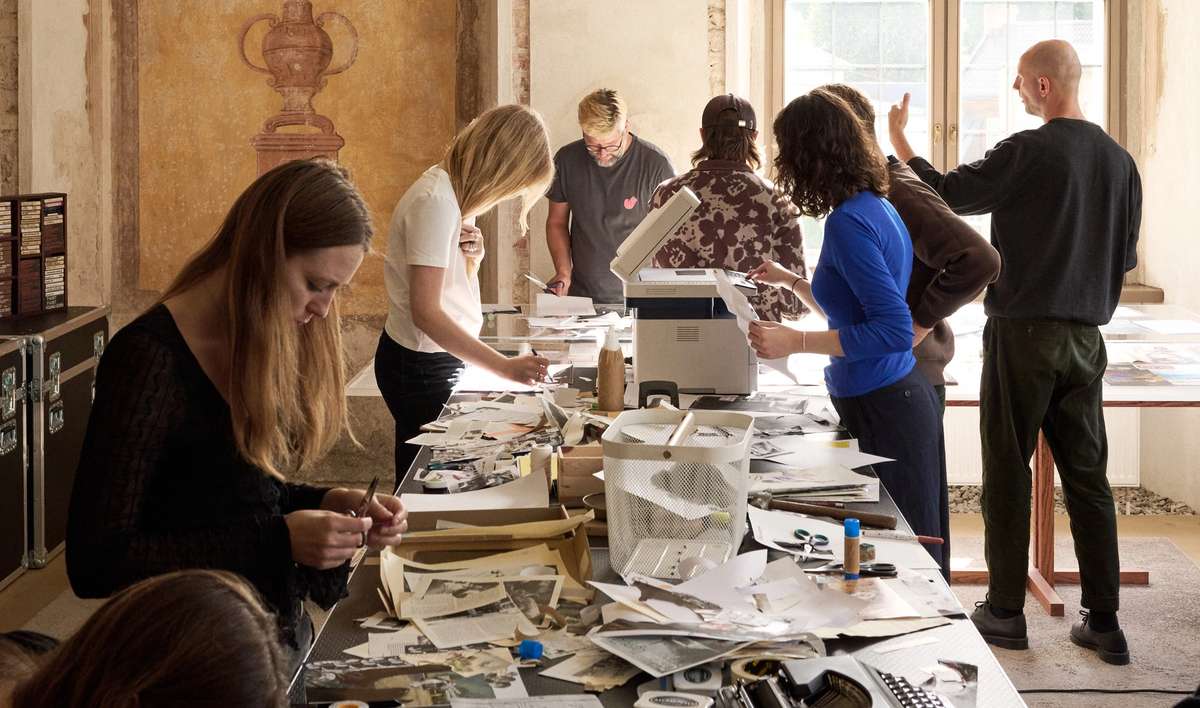 Participants cutting, gluing and copying zines at a long workshop table
